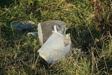 garbage from pieces of old white broken plastic bucket in green grass in nature