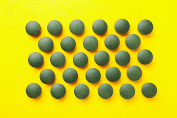 Flat lay with spirulina pills on yellow background, top view