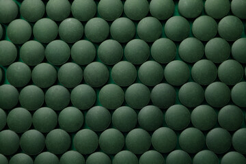 Spirulina in pills on whole background, top view