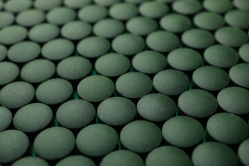 Spirulina in pills on whole background, close up