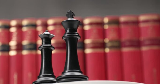 product video of black queen and king moving right and down in front of red books in a studying room