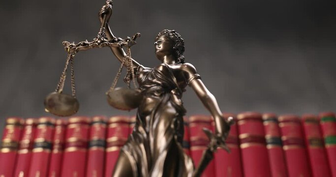justice statue represented by blindfolded lady holding a balance and a sword signifying power and impartiality, rotating in front of red books