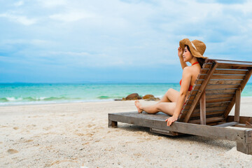 bikini woman sitting on a deck chair in the sea beach at Koh MunNork Island, Rayong, Thailand.