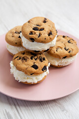 Homemade Chocolate Chip Cookie Ice Cream Sandwich on a pink plate on a white wooden background, side view.