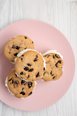 Homemade Chocolate Chip Cookie Ice Cream Sandwich on a pink plate on a white wooden table, top view. Overhead, from above, flat lay.