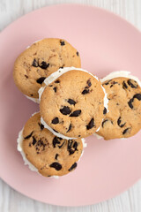Homemade Chocolate Chip Cookie Ice Cream Sandwich on a pink plate on a white wooden background, top view. Overhead, from above, flat lay. Close-up.