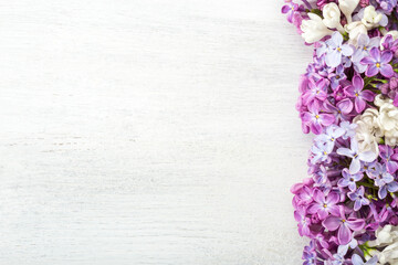 Different  tiny flowers of Lilac on the  white wooden shabby background. Floral border. Flat lay.