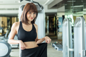 asian slim fitness woman working out in gym with waist measurement, portrait of fitness woman in...