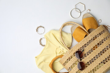 Stylish straw bag and summer accessories on white background, flat lay