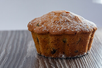 Cupcake with raisins and powdered sugar on the table. Close-up of a confectionery product. Image for project and design.