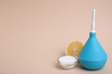 Enema, lemon and bowl of salt on beige background, space for text. Medical treatment