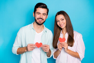 Photo of pretty charming young couple wear casual shirt holding red paper hearts isolated blue color background