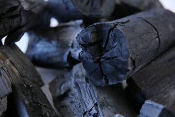 Black wood charcoal stacked on a white background.