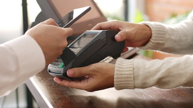 Customer using phone for payment at cafe restaurant, cashless technology and money transfer concept