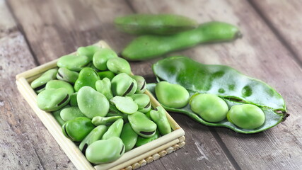 Fresh broad beans in the kitchen on old wooden background, healthy legume