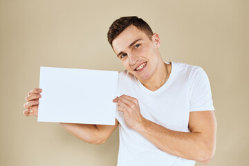 man in white t-shirt sheet of paper in hands Copy Space cropped view beige background