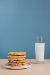 Stacked cookies in white porcelain plate and milk on the table