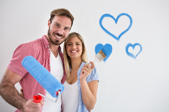 Happy young couple painting new house