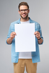 Portrait of a happy handsome young man holding blank white card or sign over white background