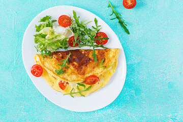 Breakfast. Omelette with tomatoes, cheese and arugula on white plate.  Frittata - italian omelet. Ketogenic, keto food. Top view, flat lay