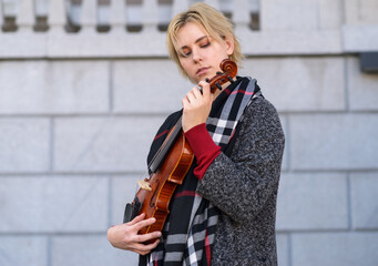 Beautiful girl in coat holding a old violin.