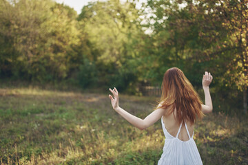 Obraz premium happy women in a sundress runs on green grass in the meadow and trees In the background
