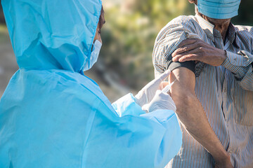 Doctor's hands in surgical gloves preparing COVID-19 vaccine for male patient in India