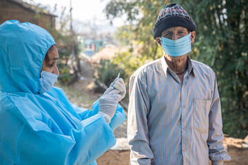Doctor's hands in surgical gloves preparing COVID-19 vaccine for male patient in India