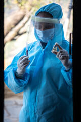 Young woman doctor in medical uniform holding a syringe and corona virus vaccine