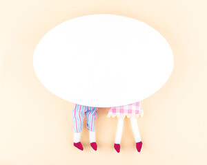 Creative minimal composition with copy space for text. Oval white blank canvas, two pairs of toy legs on a neutral beige background. Love concept. Flat lay.