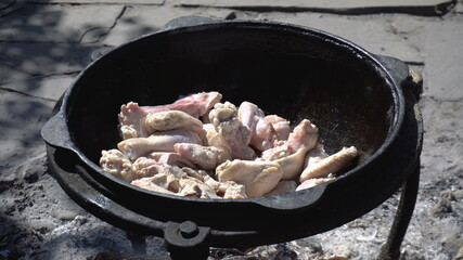Chicken is fried in a cauldron, over an open fire
