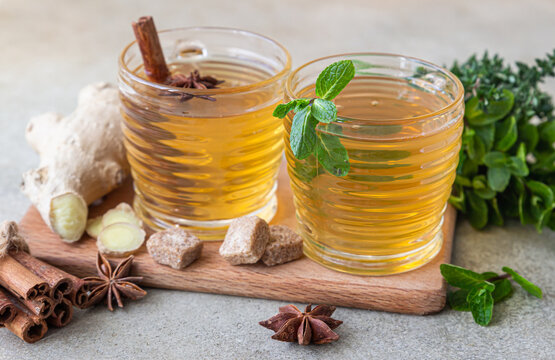 Green or herbal tea with fresh mint and thyme, cinnamon sticks, anise and ginger, light concrete background. Mint and thyme tea. - Powered by Adobe
