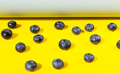 Creative pattern made of blueberries on yellow background. Berries minimal concept.