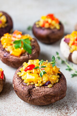 Stuffed portobello mushrooms with bulgur, vegetables and aromatic herbs on concrete background. Vegetarian food. Close up.