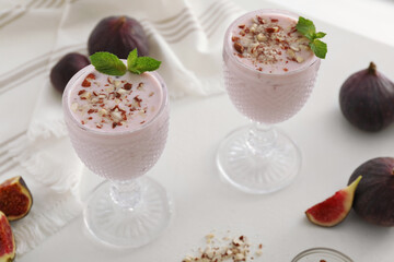 Delicious fig smoothies in glasses on white table