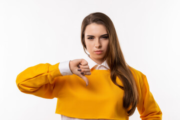 Portrait of attractive brunette girl showing thumb down. Human emotions, gesture concept. Studio shot, white background