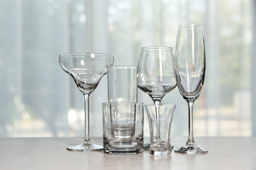 Different elegant empty glasses on grey table indoors