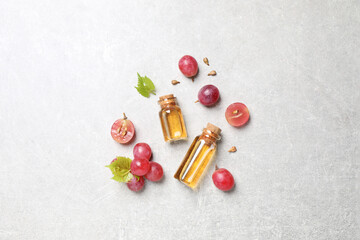 Flat lay composition with bottles of natural grape seed oil on grey table. Organic cosmetic