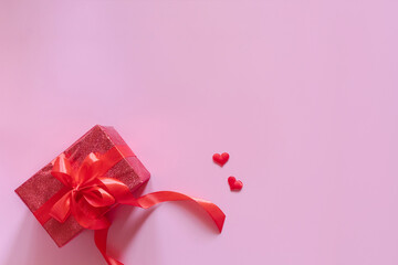 Gift red box with red bow ribbon and hearts on pink background for Valentines day. Space for text. Long wide banner.