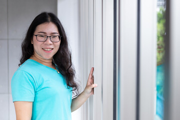 Portrait of a cheerful mature asian Wearing glasses wearing a blue Tiger stretch at the window In the office room background