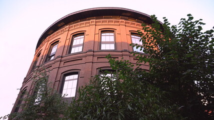 Tall cylinder-shaped building. View from behind the bushes