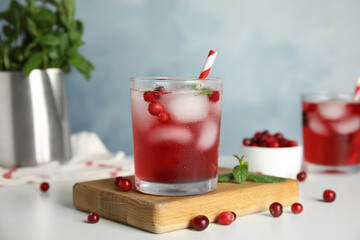 Tasty refreshing cranberry cocktail with mint on white table