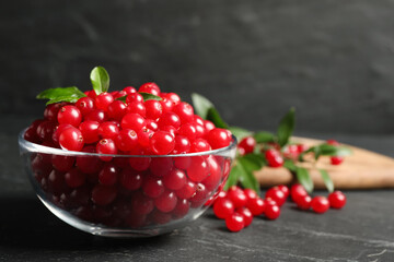 Fresh cranberry in bowl on dark grey table, space for text