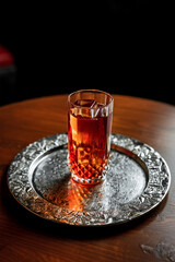 A long drink cocktail with ice in a vintage highball glass on a silver tray