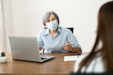 Senior elder businesswoman hr manager wearing a face mask, interviewing a job seeker, mentoring...