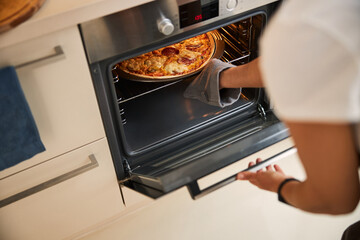Using oven mitt while taking hot baking pan