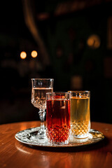 Two long drink cocktails with ice in vintage highball glasses and a glass of wine or vermouth on a silver tray