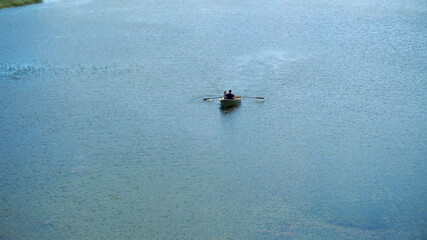 People are on a boat with oars. Boat in the blue lake
