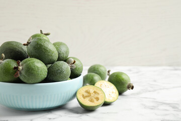 Fresh green feijoa fruits on white marble table, space for text
