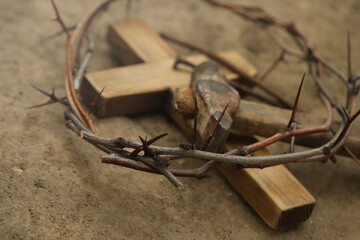 Fototapeta na wymiar Crown of thorns, wooden cross and hammer on ground, closeup. Easter attributes